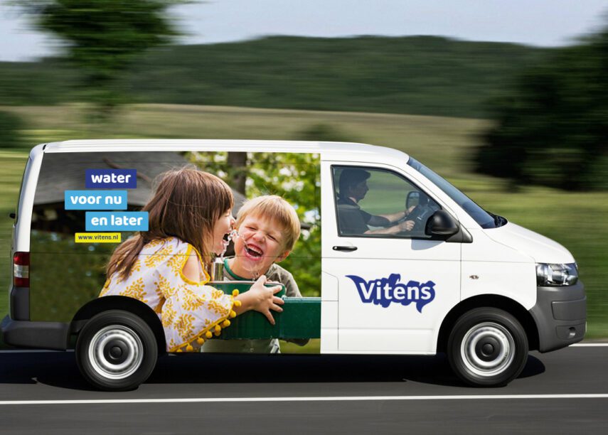 Bus van Vitens rijdend op een weg met een sticker van twee kindjes met de tekst "water voor nu en later"