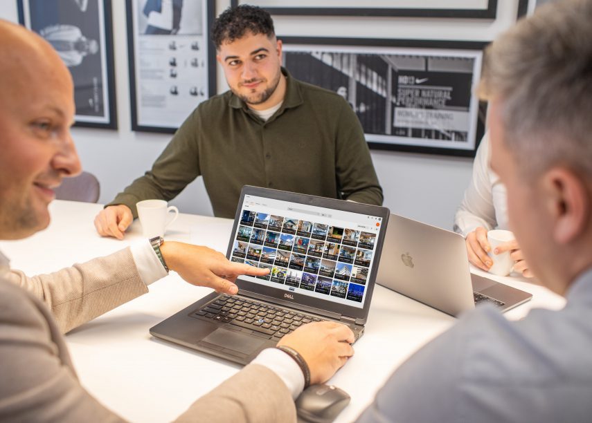 Die RGN-medewerkers werken samen aan mybrand.center, RGN's brand portal op een laptop in een vergaderruimte